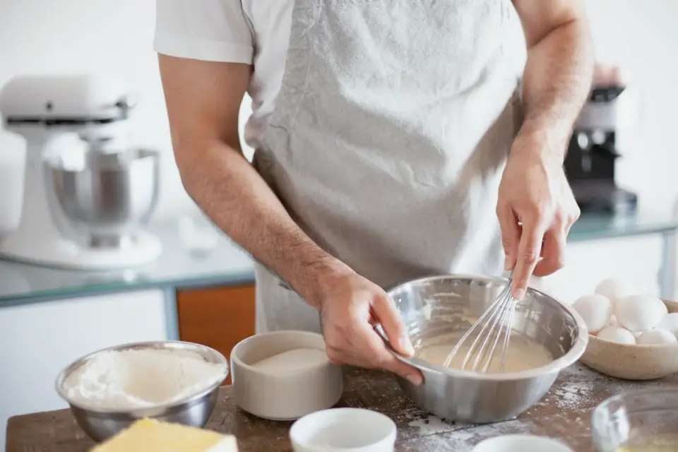 A person stirring a small amount of oil into a bowl of dog food