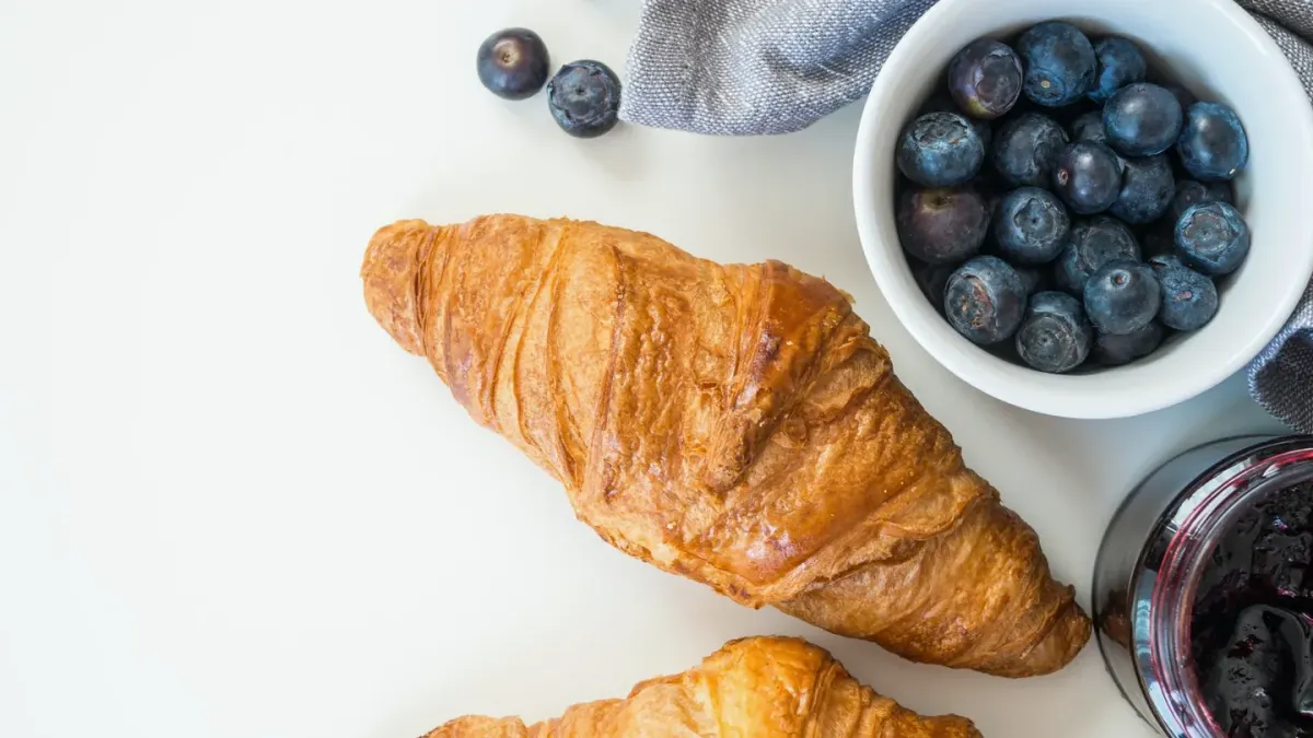 A small bowl of fresh blueberries set on a kitchen counter next to a dog's nose