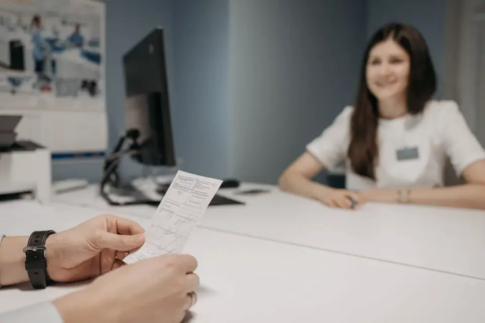 A veterinarian handing a prescription bottle to a dog owner in an exam room
