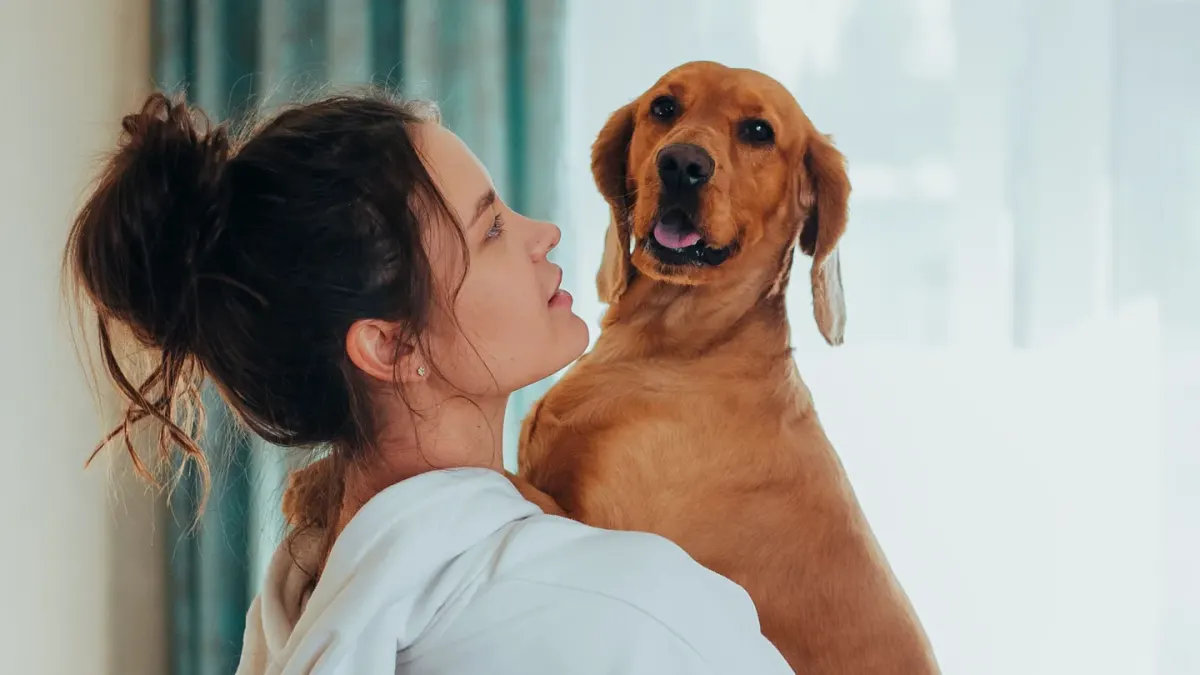 A woman standing and hugging a Labrador